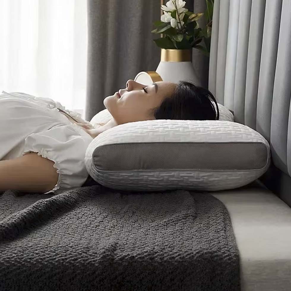 Mujer descansando cómodamente boca arriba sobre almohada cervical Perfect Dream Pillow, expresión de alivio y confort