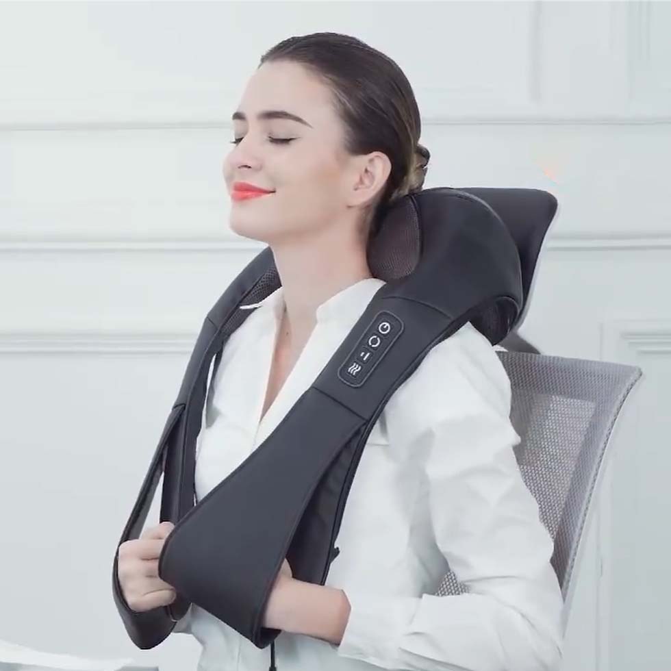 Mujer aliviando tensión cervical con masajeador shiatsu mientras trabaja en su escritorio