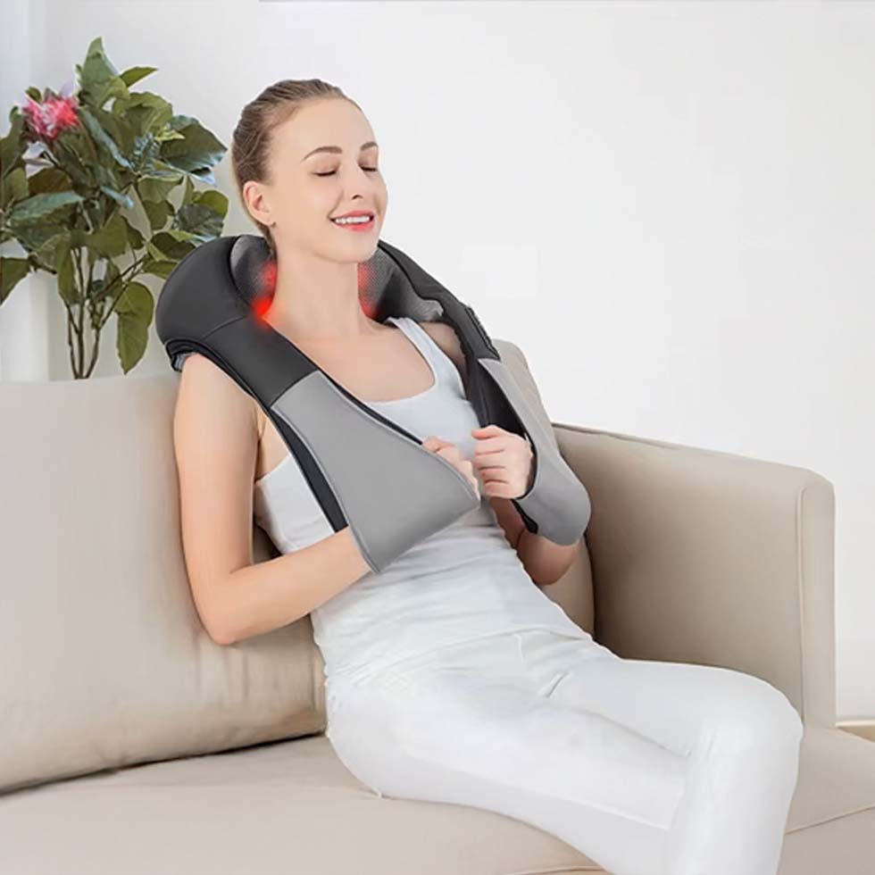 Mujer relajándose con masajeador shiatsu en el cuello, sentada en su sala de estar