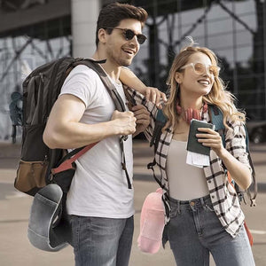 Pareja joven viajera en terminal aéreo, con mochilas y almohadas de viaje Ergo Travel Pillow sujetas a la cintura, mostrando portabilidad