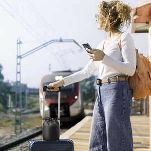 Mujer esperando tren con maleta de viaje, llevando bolsa compacta con Ergo Travel Pillow, lista para usar en trayecto largo